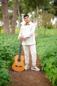 חתן בר מצווה מנגן בגיטרה בצילומי חוץ על הדשא