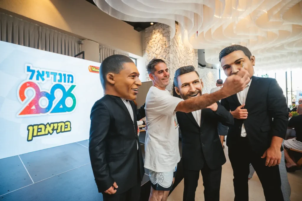 אורח מצטלם עם בובות כוכבי הכדורגל בטוקסידו באירוע חברה