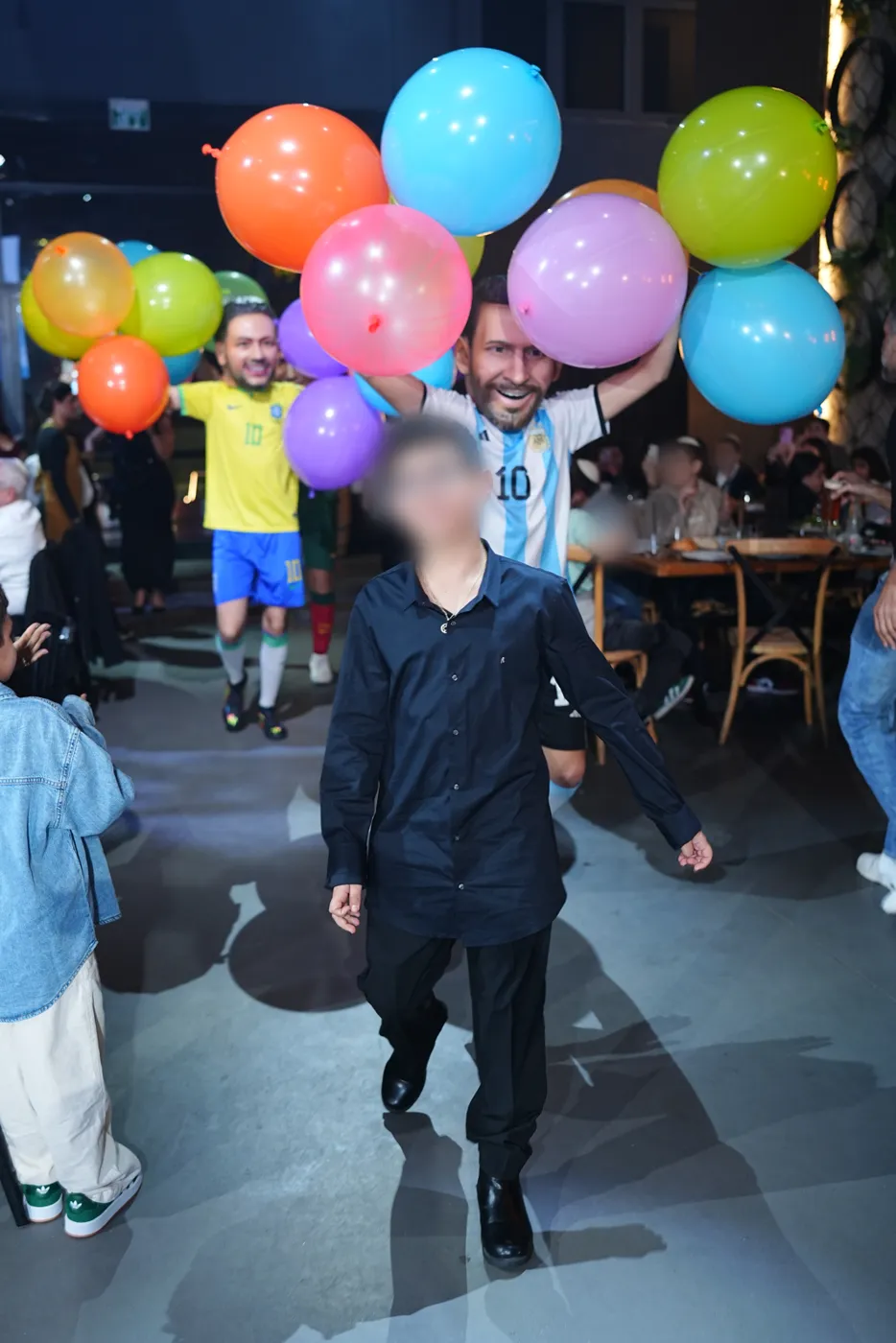 חתן בר המצווה נכנס לאירוע ומאחוריו דמויות כוכבי הכדורגל עם בלונים צבעוניים