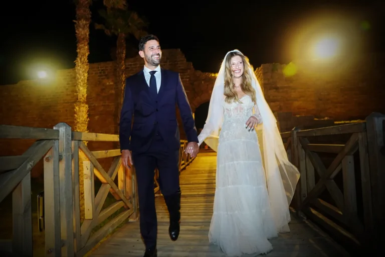 חתן וכלה הולכים יד ביד בצילומי זוג בלילה